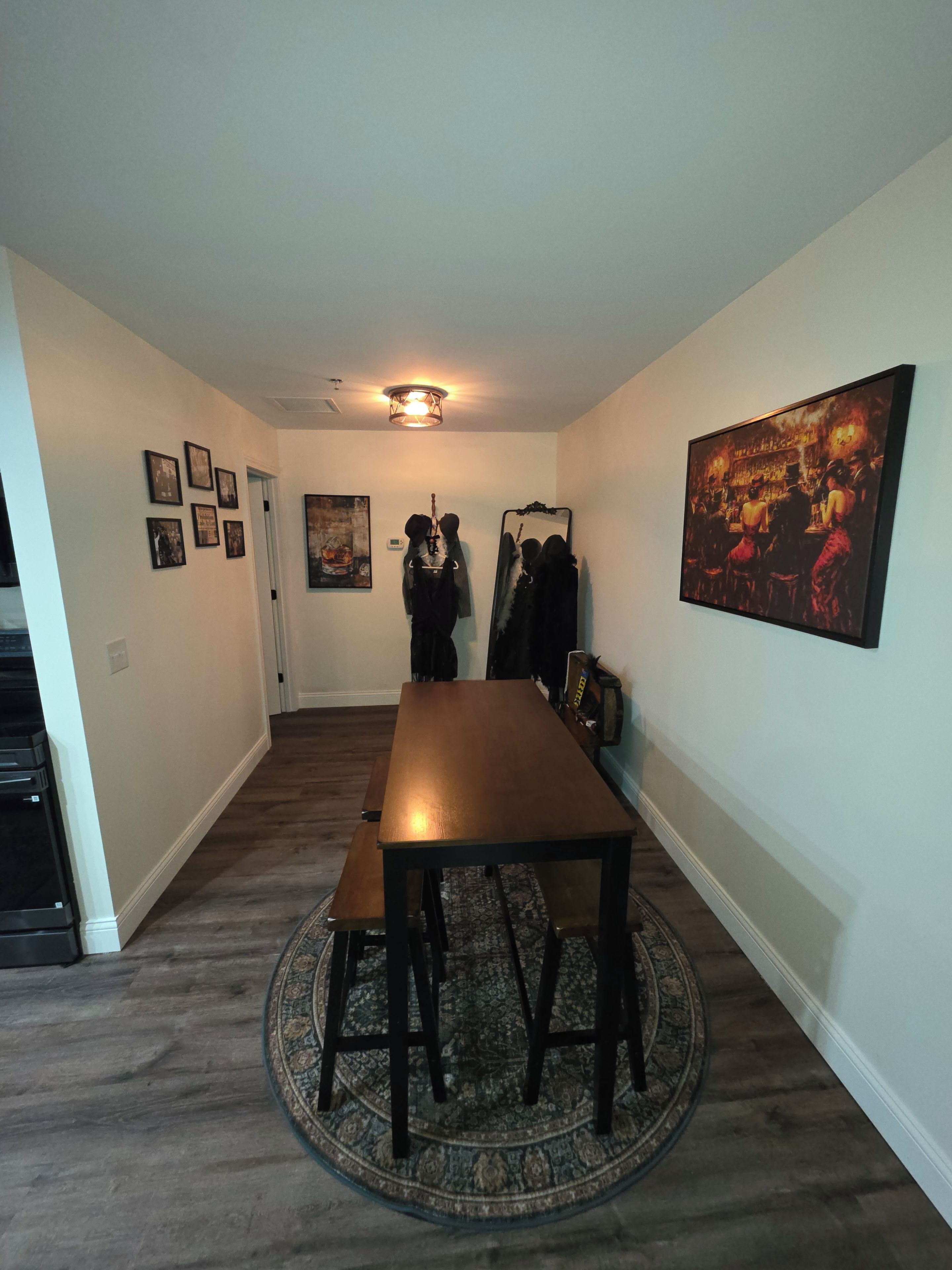 A dining area with a long table, benches, a rug, and a painting on the wall.