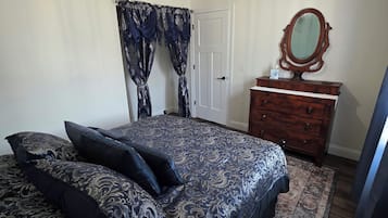 A bedroom with a bed, a dresser, a mirror, and a ceiling light fixture.