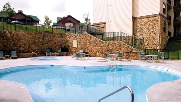 A swimming pool with lounge chairs and a stone wall.