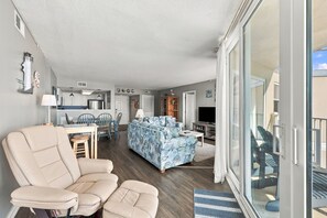 A spacious living area with a sofa, a dining table, and a kitchen in the background. - Luxury Oceanfront Escape at “Top of the Regis” (North Topsail Beach)
