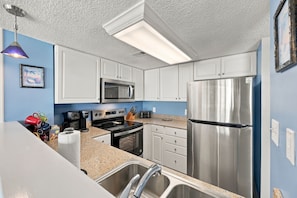 A modern kitchen with white cabinets, stainless steel appliances, a microwave, oven, and a refrigerator. - Luxury Oceanfront Escape at “Top of the Regis” (North Topsail Beach)