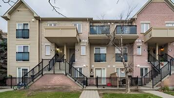 A multi-story residential building with a central staircase, balconies, and a brick facade.