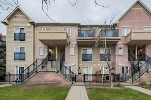 A multi-story residential building with a central staircase, balconies, and a brick facade.