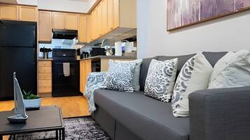 A modern living room with a grey sofa, a small table, and a decorative sailboat model.