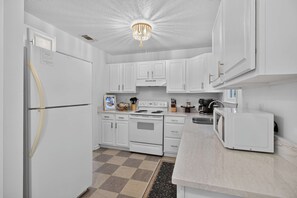 A modern kitchen with white cabinetry, a built-in oven, a microwave, and a refrigerator. - Savannah Reserve Whole House & Hot Tub Sleeps 12 (Savannah)