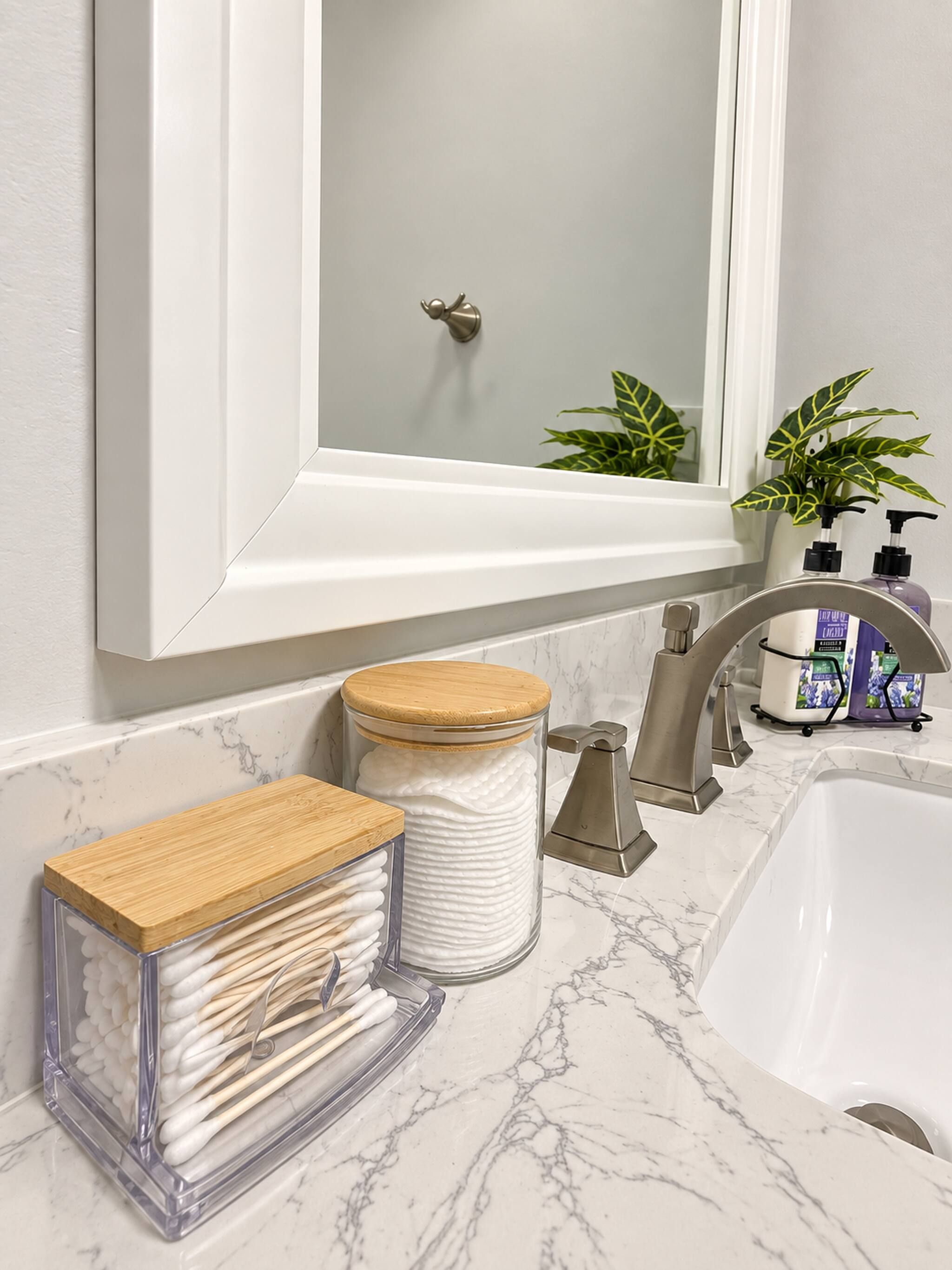 Un baño con encimera de mármol, lavabo, espejo y una planta.