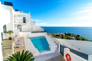 A modern hotel with a pool, a view of the sea, and a balcony with sun loungers. - Apartment in Nerja With Panoramic Sea Views (Nerja)