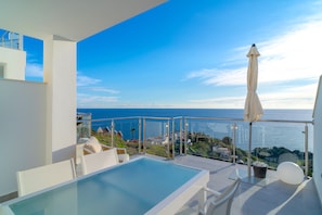 A modern balcony with a glass balustrade, a pool, and a view of the sea. - Apartment in Nerja With Panoramic Sea Views (Nerja)