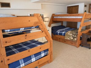 A room with bunk beds, a nightstand, and a small desk. - Beautiful Gun Lake Cottage – Private Lakefront, Sandy Bottom & Lots of Lake Toys (Middleville)