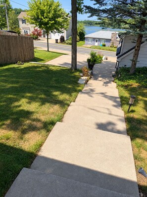 A residential driveway leading to a house with a lawn and a tree. - Beautiful Gun Lake Cottage – Private Lakefront, Sandy Bottom & Lots of Lake Toys (Middleville)