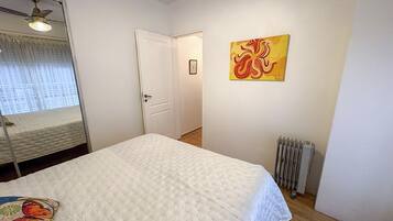 Ein Schlafzimmer mit einem Bett, einem Heizkörper, einer Tür und einem Bild an der Wand.