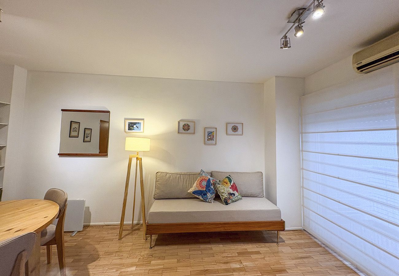 A room with a sofa, a table, and a lamp.