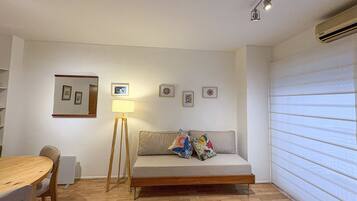 A room with a sofa, a table, and a lamp.