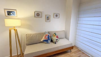 A room with a sofa, a floor lamp, and three framed pictures on the wall.