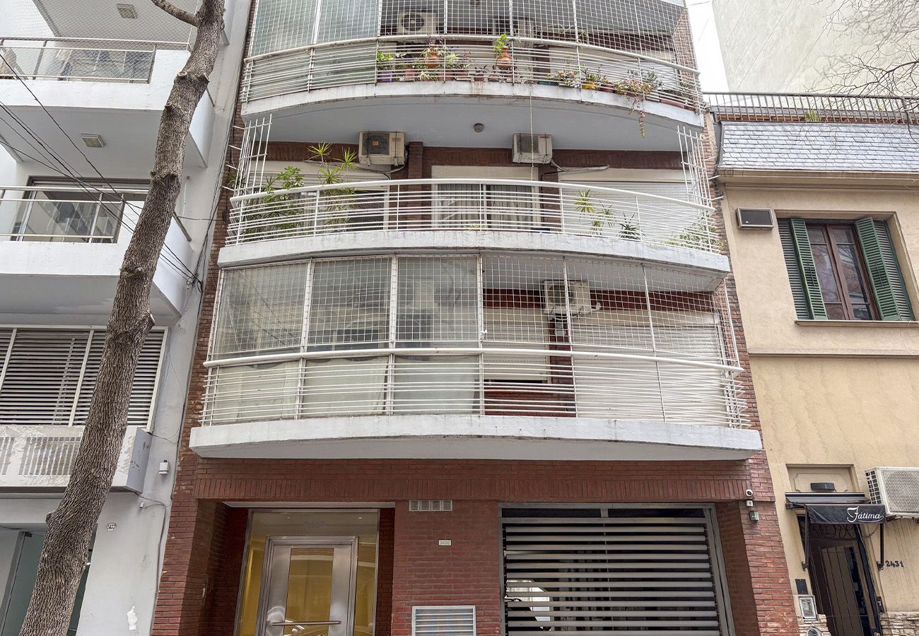 Edifício com várias andares, varandas, aparelhos de ar condicionado e fachada com uma placa.