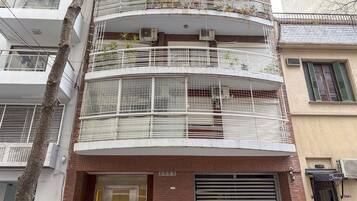 Edifício com várias andares, varandas, aparelhos de ar condicionado e fachada com uma placa.