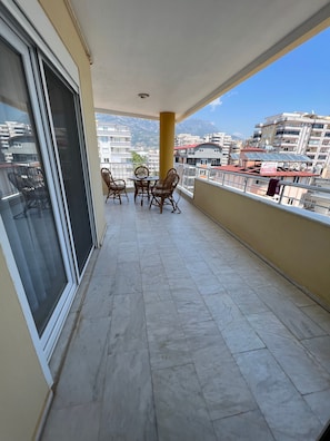 Ein Balkon mit Tisch und Stühlen, Blick auf die Stadt und ein Gebäude mit einem Schild.
