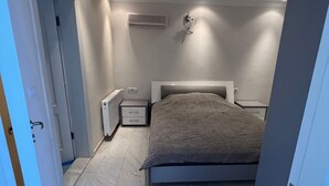 A bedroom with a bed, bedside tables, an air conditioning unit, and a door leading to another room. - Spacious 2-story penthouse with 2 terraces, views of the sea and mountains. (Mahmutlar)