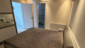A bedroom with a bed, a radiator, a door leading to a bathroom, and a window. - Spacious 2-story penthouse with 2 terraces, views of the sea and mountains. (Mahmutlar)