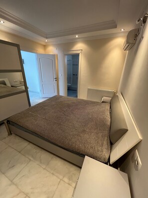 Ein Schlafzimmer mit einem Bett, einem Heizkörper, einer Tür zu einem Badezimmer und einem Fenster.