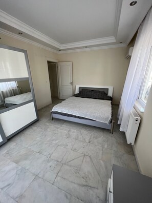 Un dormitorio con cama, espejo, radiador y puerta.