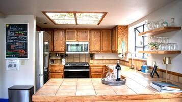 A modern kitchen with wooden cabinets, a central island, and a chalkboard menu on the wall.