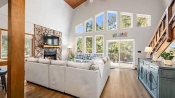 A spacious living area with a large sectional sofa, a fireplace, and a view of the outdoors through multiple windows.