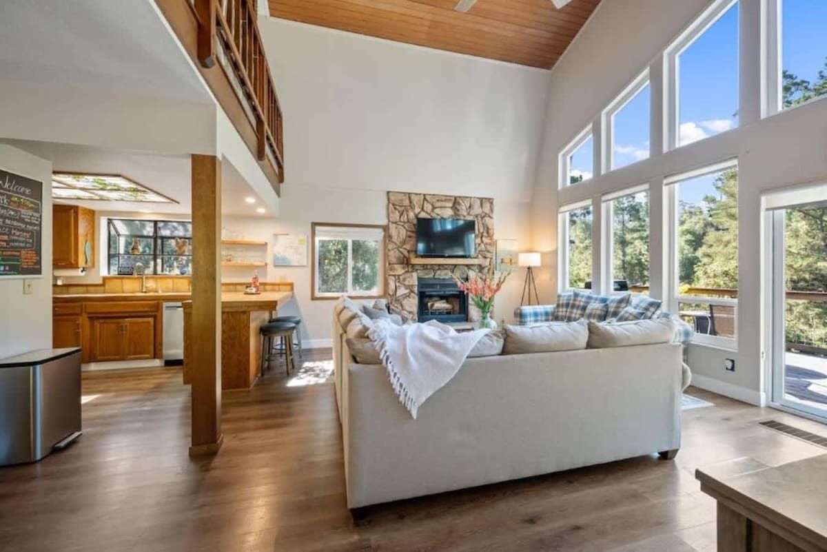 A spacious living area with a fireplace, a sofa, and a dining area with a view of the outdoors.