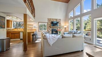 A spacious living area with a fireplace, a sofa, and a dining area with a view of the outdoors.