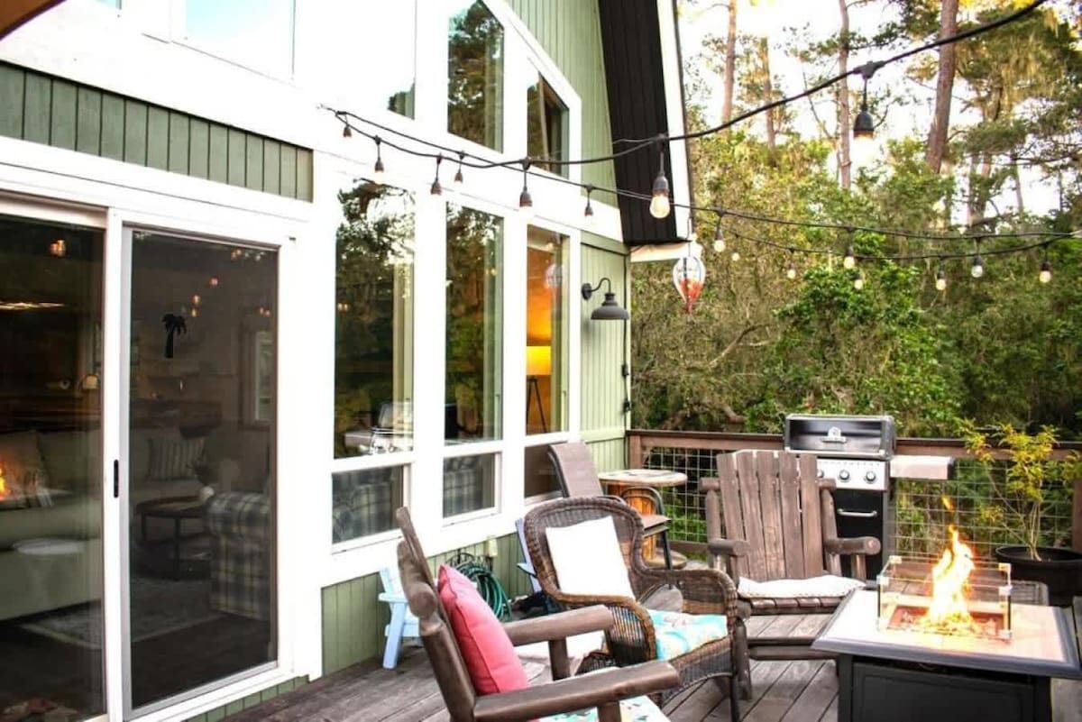 An outdoor patio with a grill, chairs, and string lights.