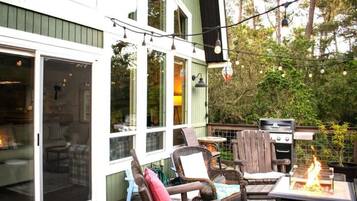 An outdoor patio with a grill, chairs, and string lights.