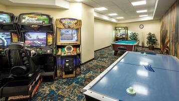 A hotel room with arcade games, a pool table, and a billiards table.