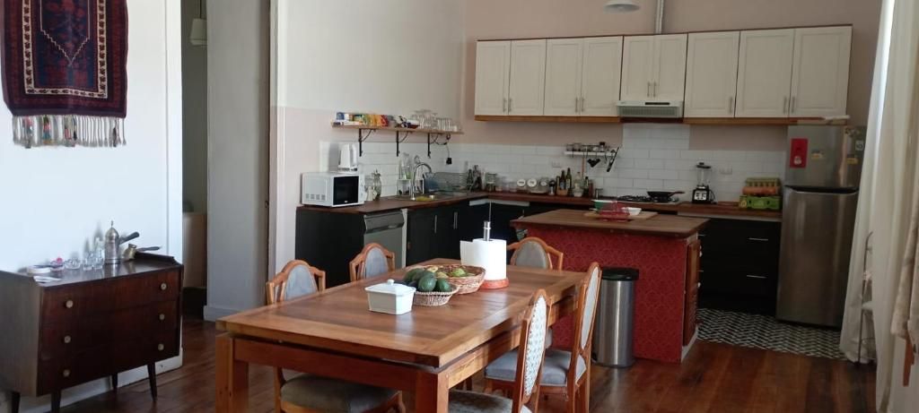 Una cocina compacta con armarios blancos, una mesa de comedor con sillas y una pequeña isla con un lavamanos.