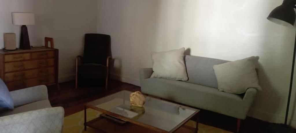 A living room with a sofa, a chair, a coffee table, a lamp, and a dresser.