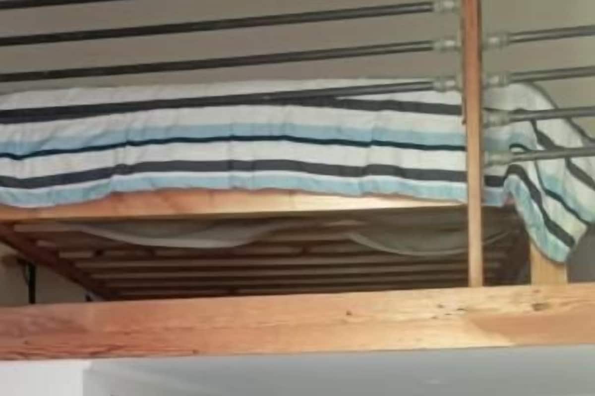 A room with a bunk bed, a door, and a single bed with a blue bedspread.