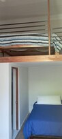 Una habitación con una litera, una puerta y una cama individual con colcha azul.