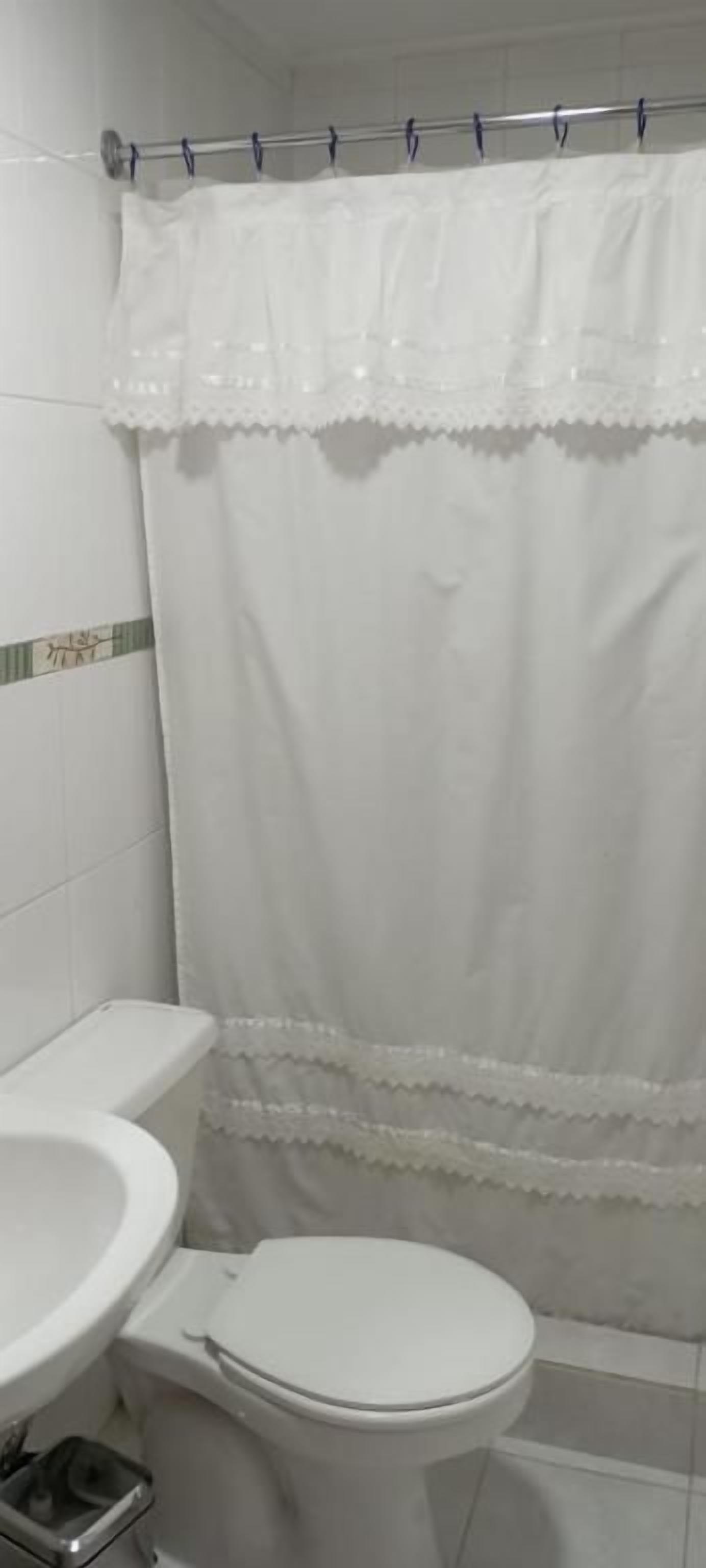 Un baño con inodoro, lavabo y cortina de ducha.