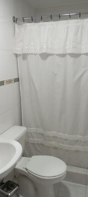 Un baño con inodoro, lavabo y cortina de ducha.