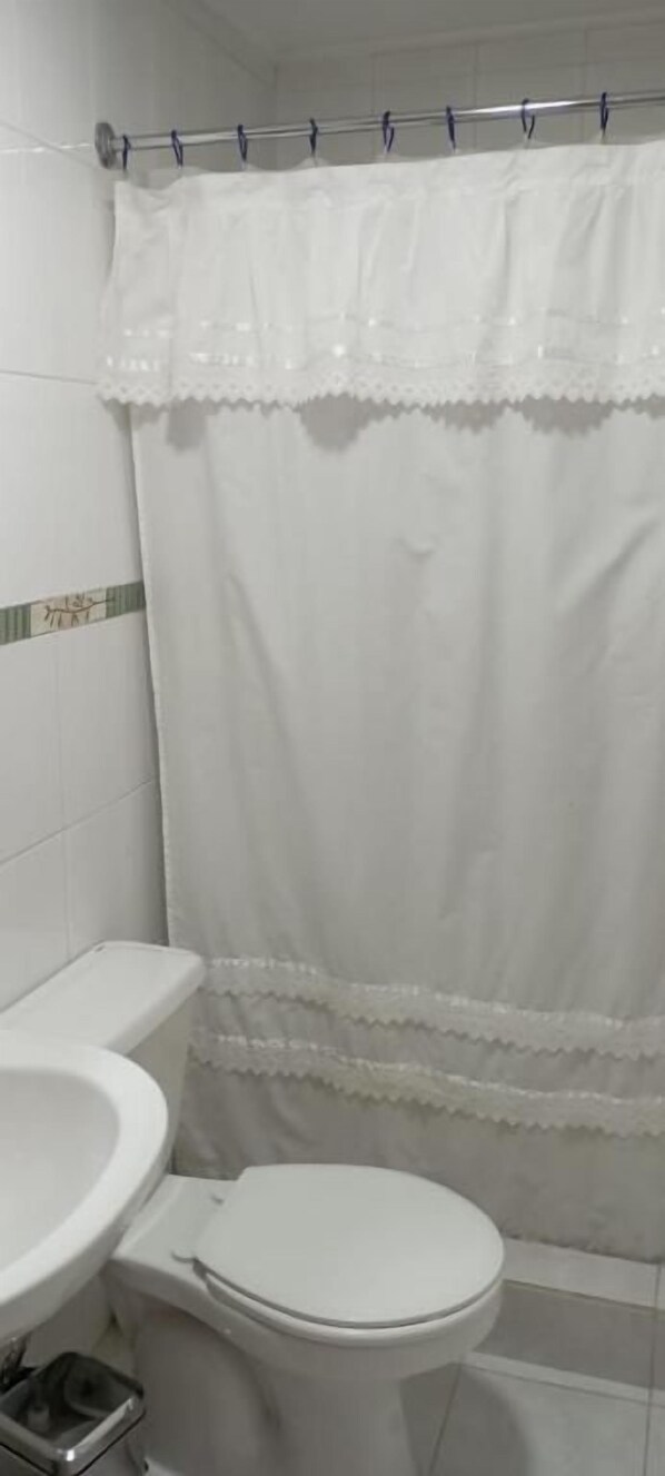 Un baño con inodoro, lavabo y cortina de ducha.