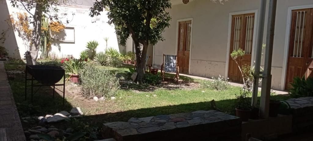 A courtyard with a small garden, a wheelbarrow, and a building with wooden doors and windows.