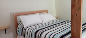 Una cama con una colcha a rayas y dos almohadas blancas.