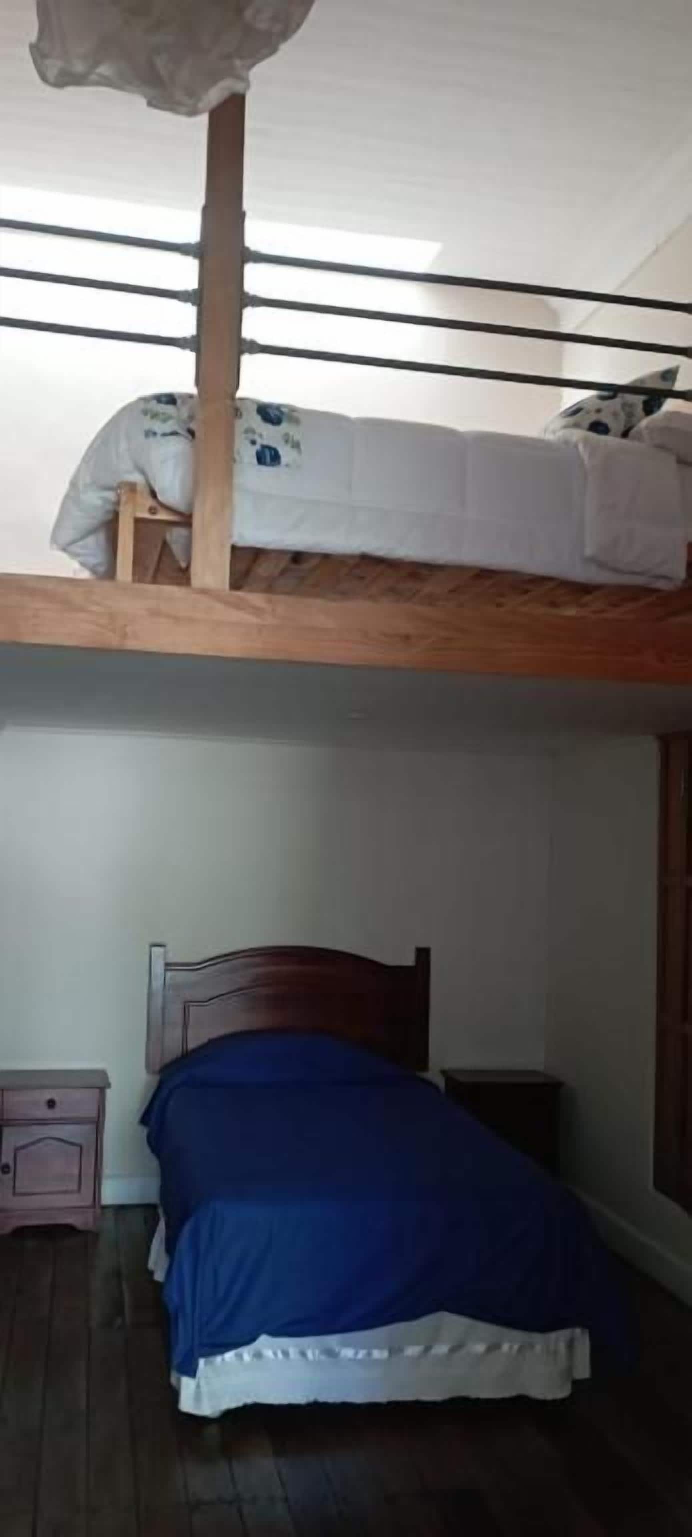 Una cama litera con una cama inferior, una mesita de noche y un buró.