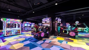 Um salão de jogos indoor com várias máquinas de jogos e um padrão geométrico colorido no chão.