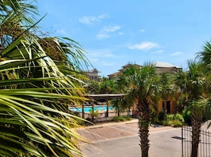 A pool area with a clear sky, palm trees, and a building with a dome roof. - Miramar Beach Villa 112 (Miramar Beach)