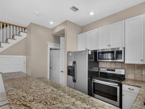 A kitchen with granite countertops, stainless steel appliances, and white cabinetry. - Miramar Beach Villa 112 (Miramar Beach)
