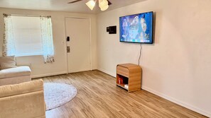 A living room with a sofa, a television mounted on the wall, and a wooden cabinet. - Tower View...Pet-Friendly 2BR Retreat...Beverly Hills (Beverly Hills)
