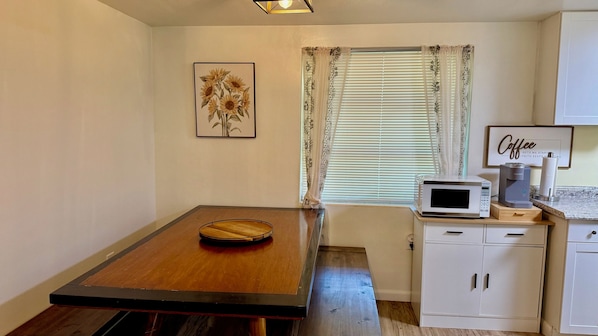 A small kitchenette with a microwave, coffee maker, and a framed picture of sunflowers.