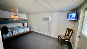 Ett rum med våningssängar, en tv, en stol och en dörr.
