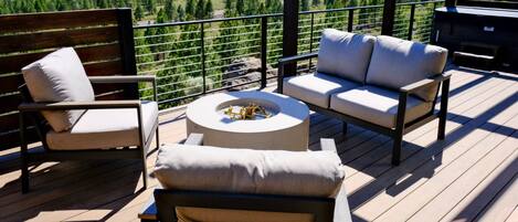 A deck with outdoor furniture, including a sofa and chairs, and a round table with a decorative item.
