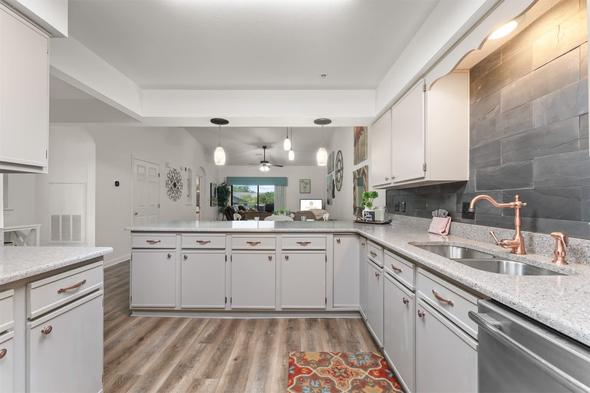 A modern kitchen with white cabinetry, a granite countertop, and copper faucets.